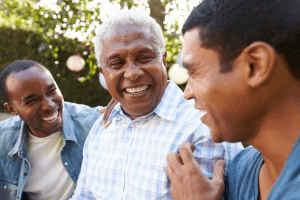 3 men of various ages talking and laughing with each other in a park.